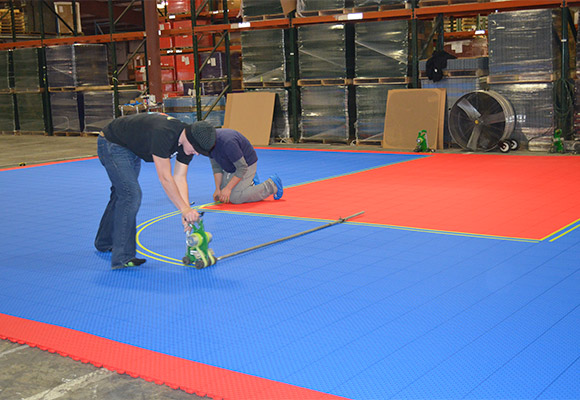 professionals pre-painting court lines on tiles in warehouse